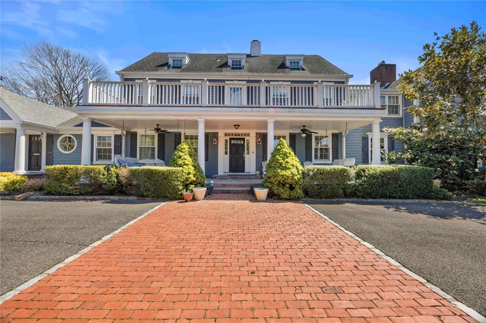 View of front of home with a ceiling fan, a balcony, a chimney, and covered porch