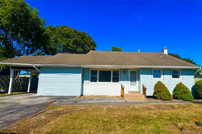 Single story home with a chimney, asphalt driveway, a shingled roof, and an attached carport