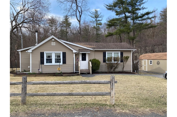 View of front of property with fence, a shed, entry steps, an outdoor structure, and a front lawn