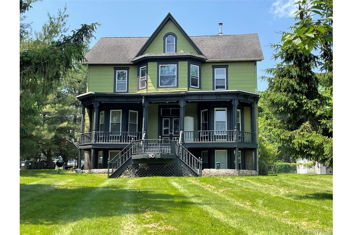 Victorian house featuring stairs, a porch, a front lawn, and a shingled roof
