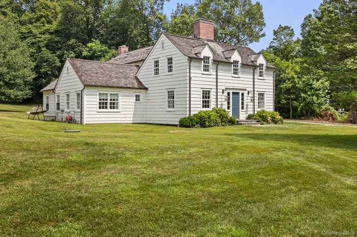 View of front of property with a front lawn, a chimney, and view of scattered trees