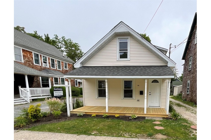 Back of property with a porch and a shingled roof
