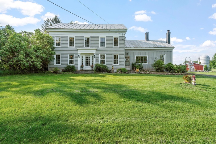 Back of house with a metal roof, a lawn, and a chimney