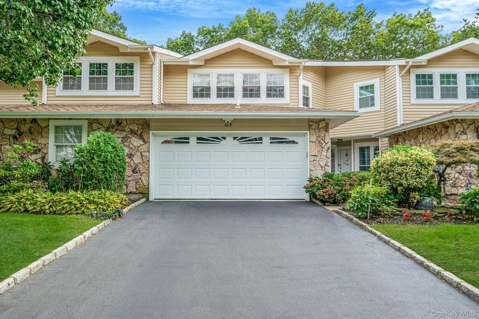 Traditional-style house with stone siding, asphalt driveway, and an attached garage