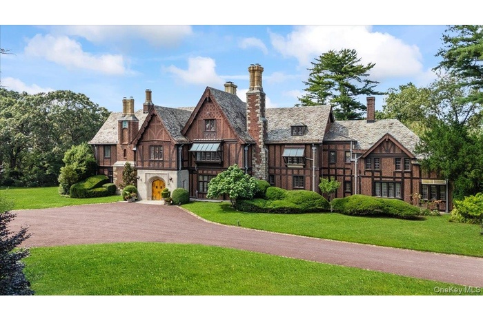 The Chimney's -Tudor style mansion featuring a front lawn, a chimney, and driveway