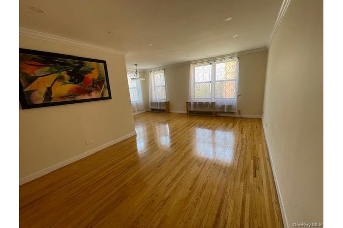 Empty room with light wood-type flooring and ornamental molding