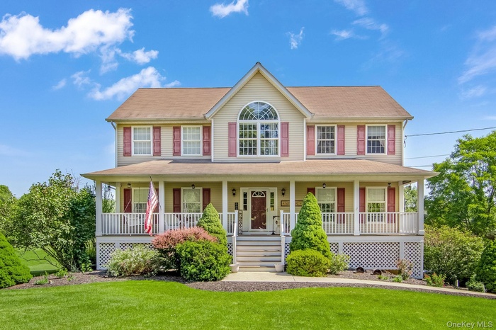 Colonial home featuring a porch and a front lawn