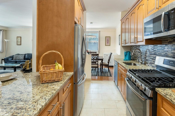 Kitchen featuring stainless steel appliances, a sink, tasteful backsplash, ornamental molding, and light stone countertops