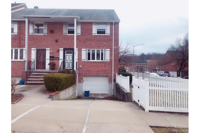 View of front of home featuring a garage, concrete driveway, brick siding, and fence