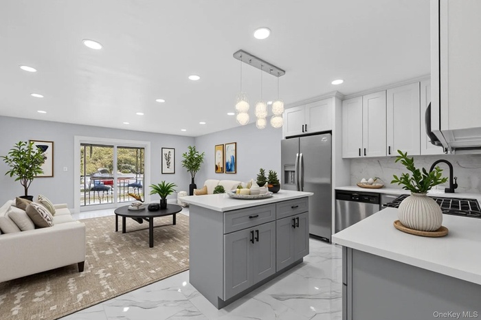 Kitchen featuring open floor plan, light marble finish flooring, decorative light fixtures, appliances with stainless steel finishes, and recessed lig