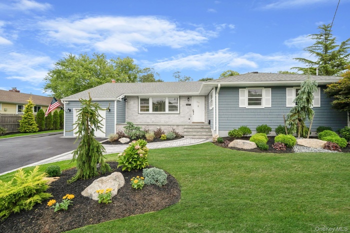 Ranch-style house featuring a front lawn, asphalt driveway, a shingled roof, and a garage