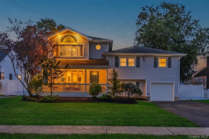 View of front facade featuring covered porch, asphalt driveway, a garage, and a gate