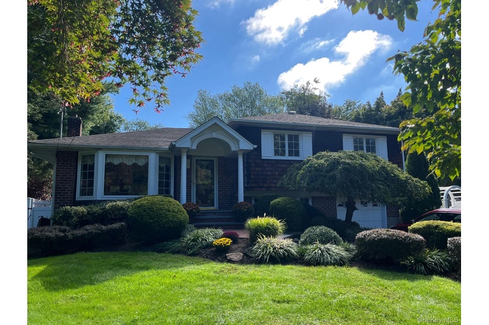 View of front of house featuring a front lawn, a chimney, and brick siding