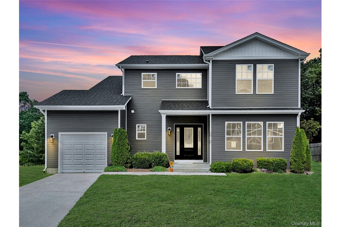 Traditional home featuring a lawn, driveway, roof with shingles, and a garage