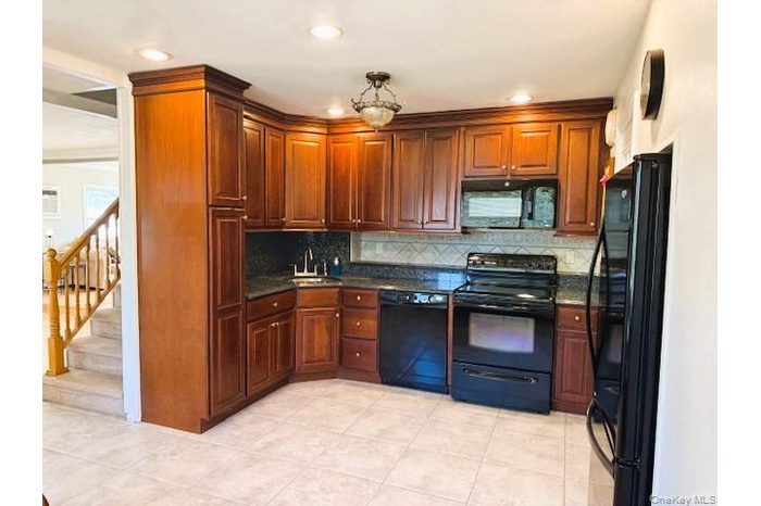Kitchen featuring black appliances, backsplash, light tile patterned floors, dark stone counters, and recessed lighting