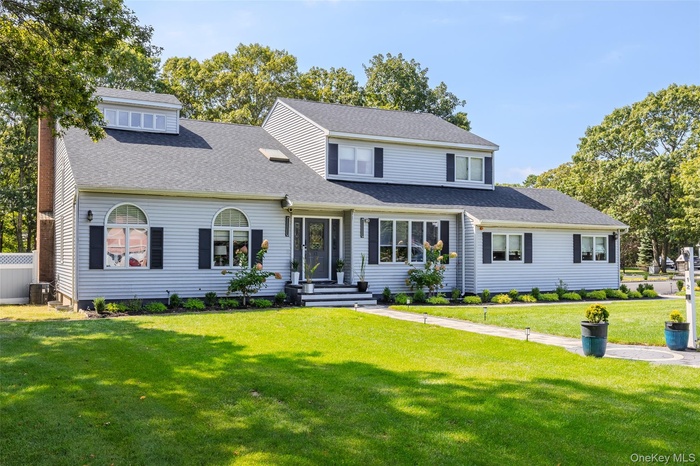 View of front facade featuring a front lawn and a shingled roof