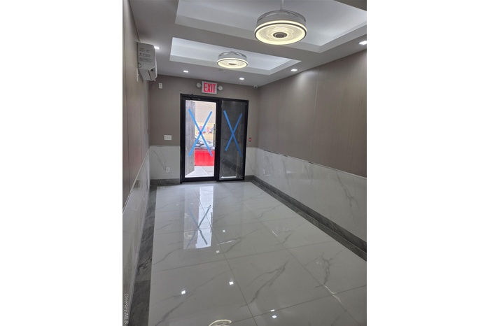 Unfurnished room featuring marble tiled flooring, a wainscoted wall, a raised ceiling, recessed lighting, and inlaid floor details