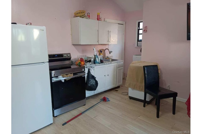 Kitchen featuring freestanding refrigerator, stainless steel range with electric cooktop, light countertops, and white cabinetry