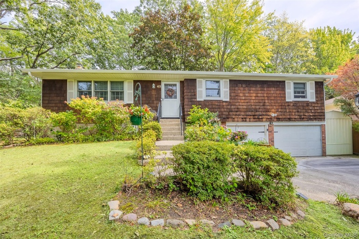 View of front of property with concrete driveway, a garage, a front yard, and entry steps