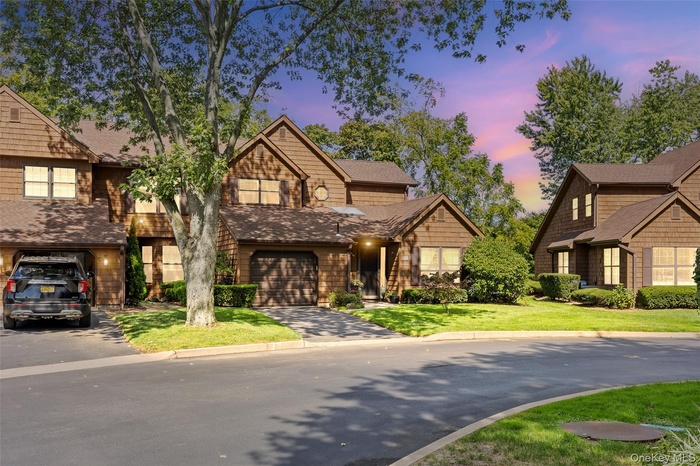 View of front of house featuring driveway, a garage, and a lawn