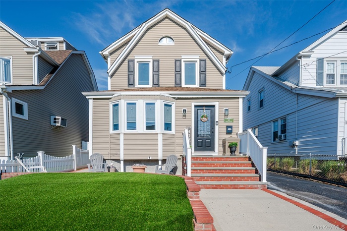 View of front facade with an AC wall unit and a gambrel roof
