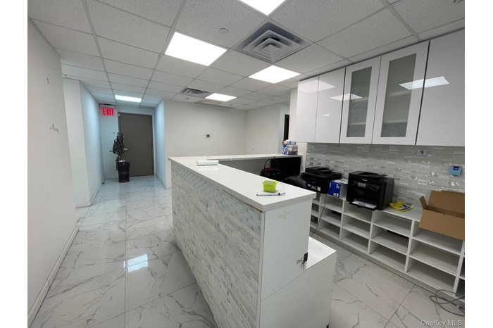 Kitchen with modern cabinets, white cabinets, glass insert cabinets, light marble finish floors, and a paneled ceiling