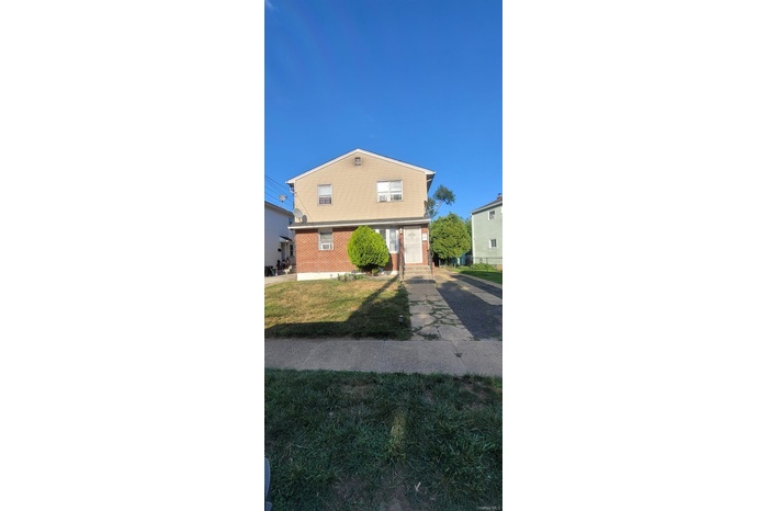 View of front of house with brick siding, an attached garage, and a front yard
