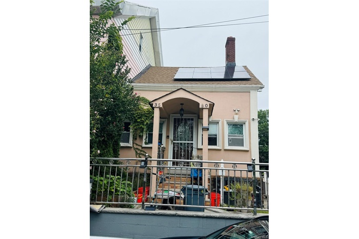 Property entrance with a chimney, roof with shingles, roof mounted solar panels, and stucco siding