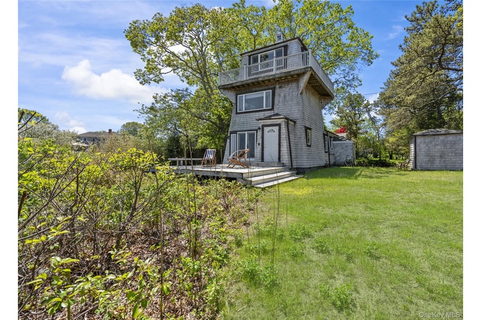 Rear view of property featuring a balcony, a yard, and a wooden deck
