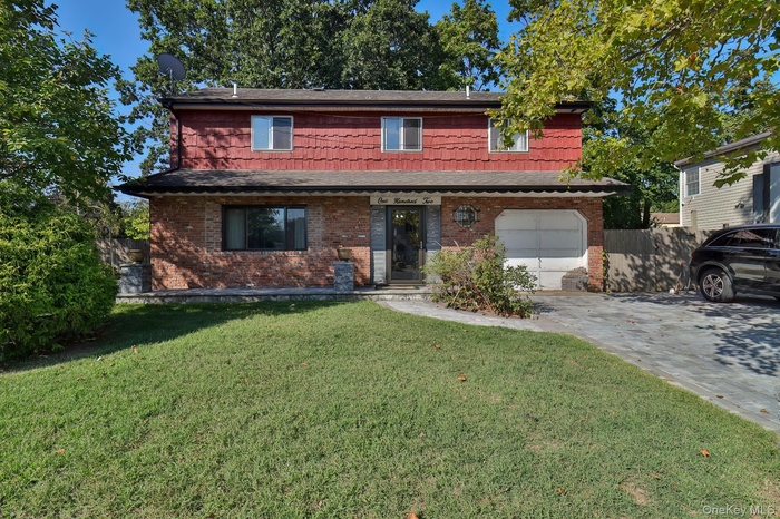 Traditional-style house featuring brick siding, driveway, an attached garage, and a shingled roof