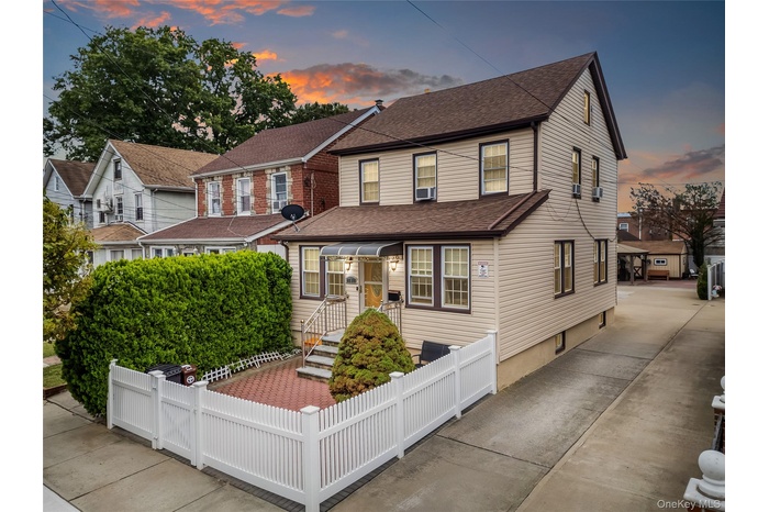 Traditional home with roof with shingles and a fenced front yard