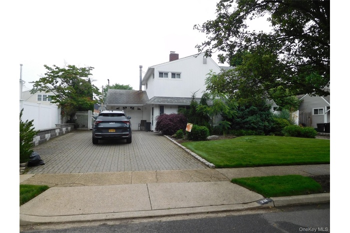View of front facade with driveway, an attached garage, and a chimney