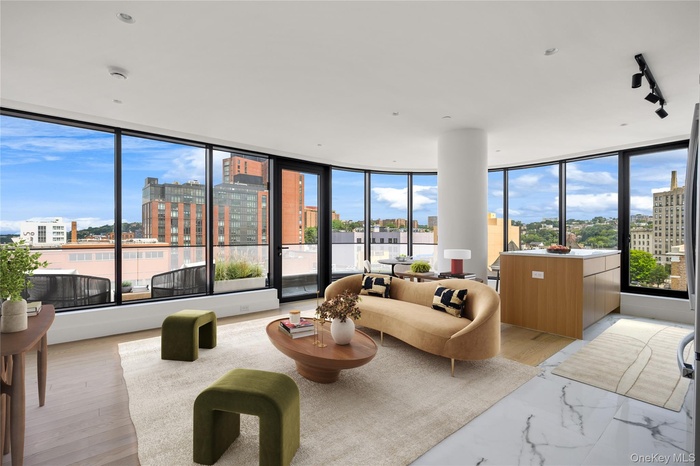 Living area with a view of city, a wall of windows, track lighting, and light wood-style flooring