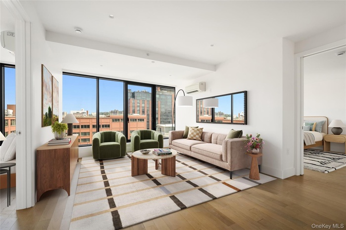 Living area with light wood-type flooring and an AC wall unit