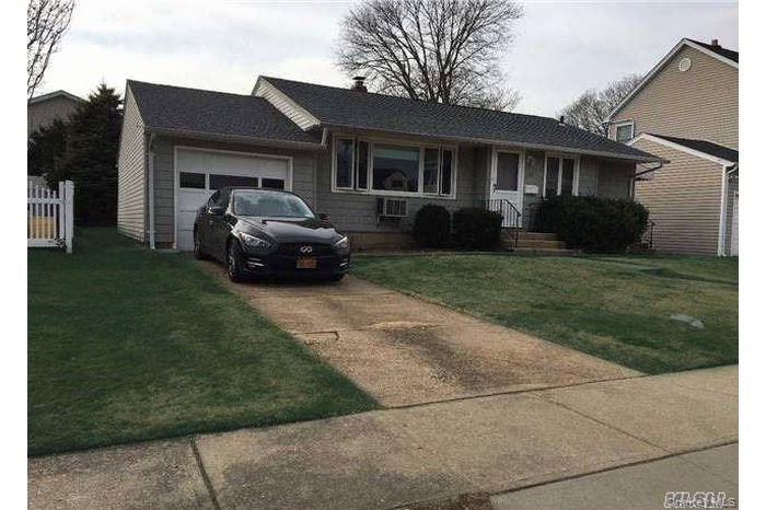 Ranch-style house featuring concrete driveway, a garage, and a front lawn