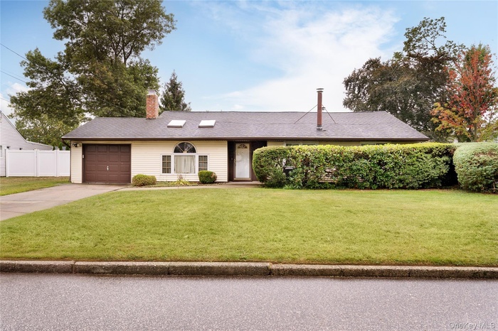 Single story home with driveway, a chimney, a shingled roof, and an attached garage