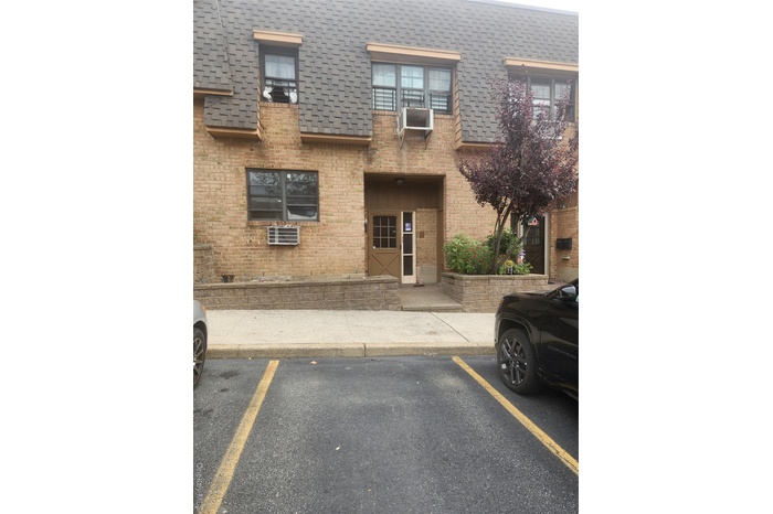 View of property with uncovered parking and a wall mounted air conditioner