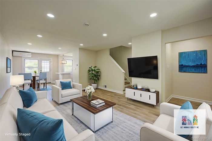 Living area with light wood-style floors, recessed lighting, stairs, and a wall mounted air conditioner