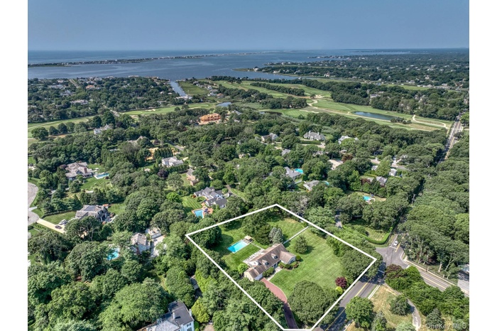 Aerial view of property's location featuring a large body of water, property parcel outlined, and a tree filled landscape