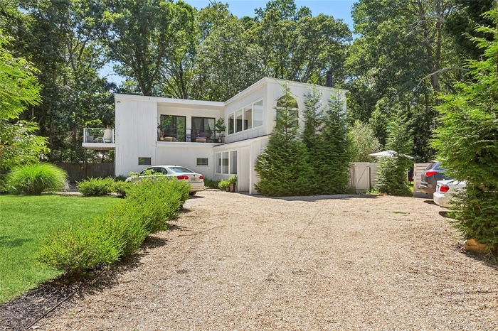 Back of house featuring driveway and a balcony
