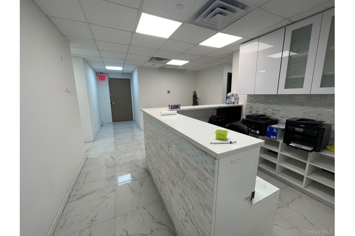 featuring modern cabinets, white cabinetry, a peninsula, a paneled ceiling, and decorative backsplash
