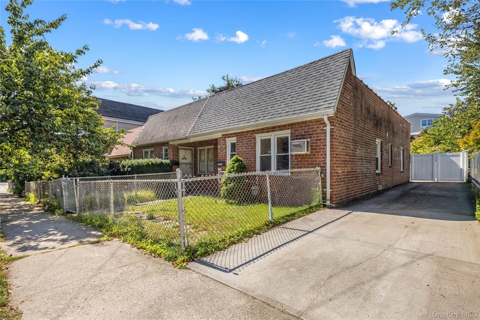 View of front of property featuring brick siding, a fenced front yard, a gate, roof with shingles, and concrete driveway