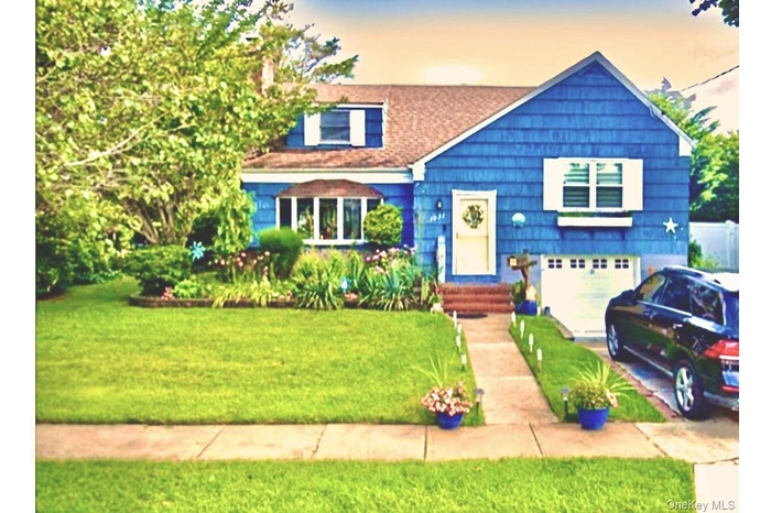 View of front of property featuring driveway, a garage, a front lawn, and roof with shingles