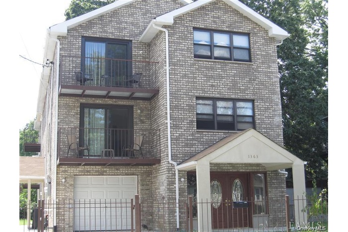 View of front of home with a balcony and brick siding