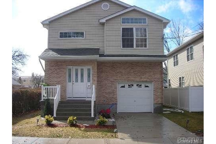 View of front of house featuring an attached garage, driveway, and brick siding