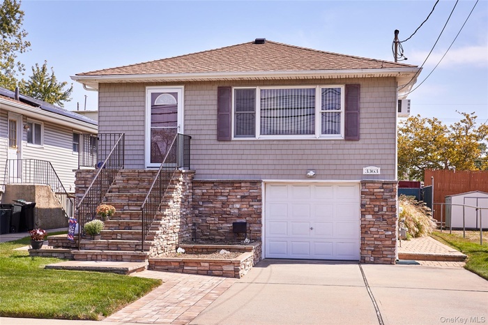 View of front of house with a shingled roof, stone siding, concrete driveway, and stairway