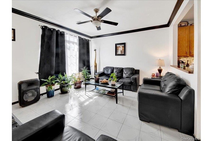 Living room with ornamental molding and ceiling fan