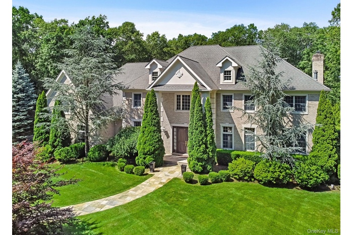 View of front of property featuring a front yard, brick siding, a chimney, and roof with shingles