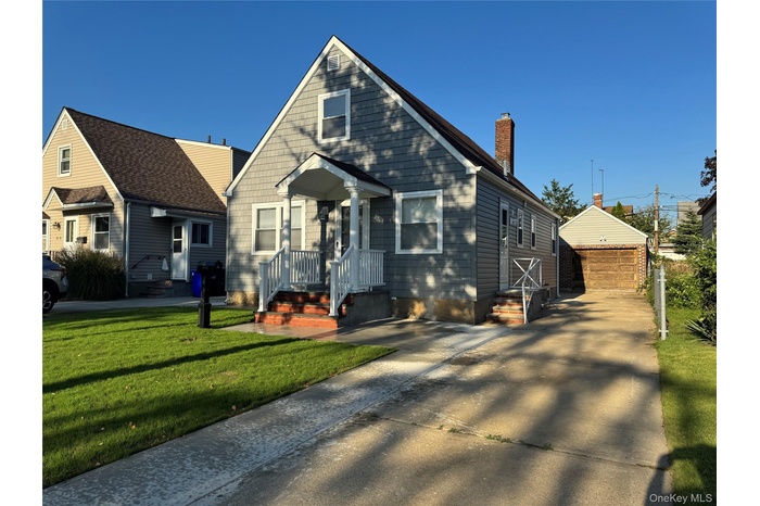 View of front of house with an outbuilding, a chimney, a garage, and a front lawn