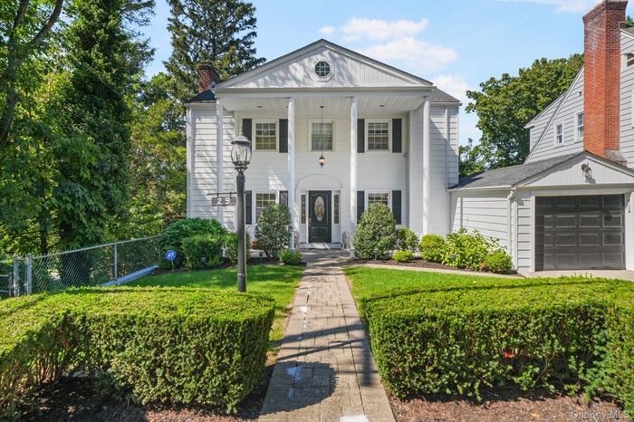 Neoclassical home with a porch, a garage, and a chimney